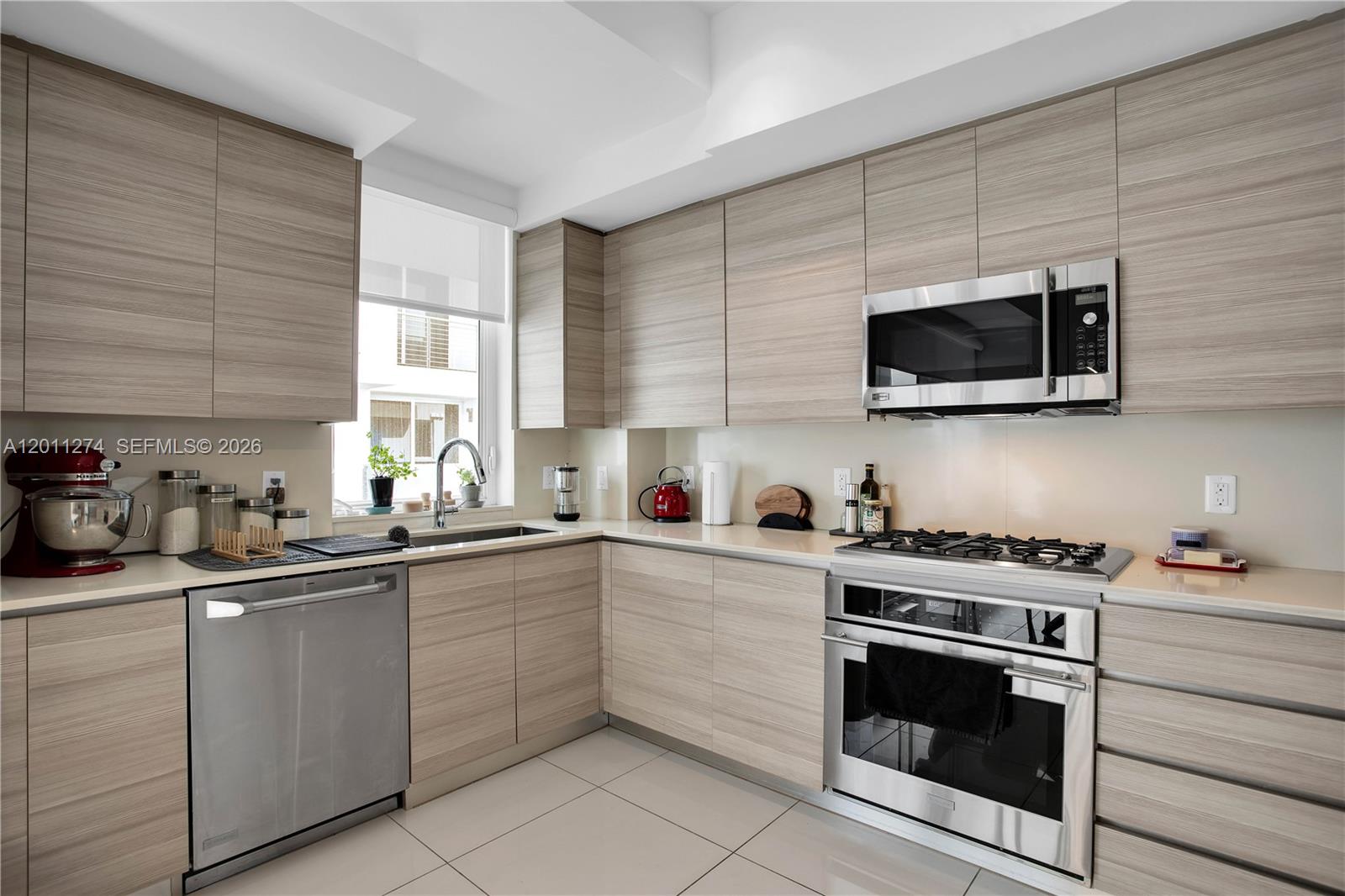 A modern kitchen features light wood cabinets, stainless steel appliances, and a corner sink — 87 N Shore Dr, Miami Beach FL 33141, MIAMI BEACH, FL