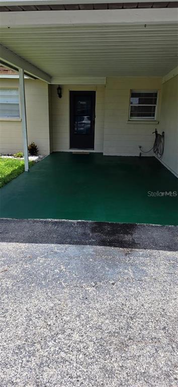 A covered carport features a green painted floor leading to a dark front door — 4608 PARK ACRES DRIVE, BRADENTON, FL