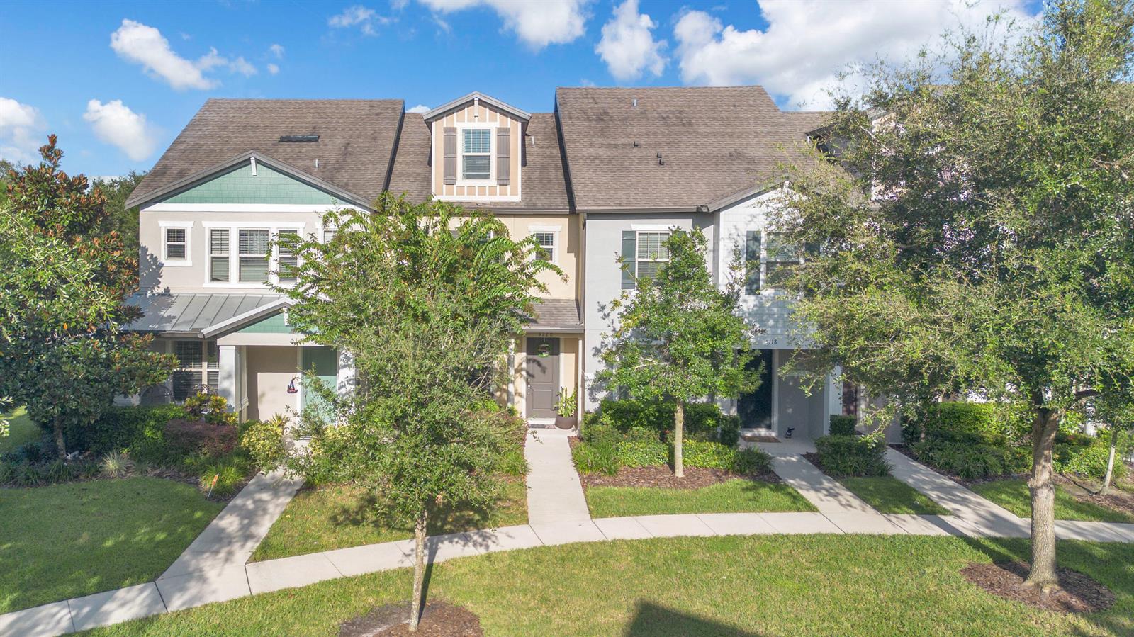 A row of multi-story townhomes with light-colored siding, gabled roofs, and front walkways — 5120 Caspian Street, FL 34771, FL