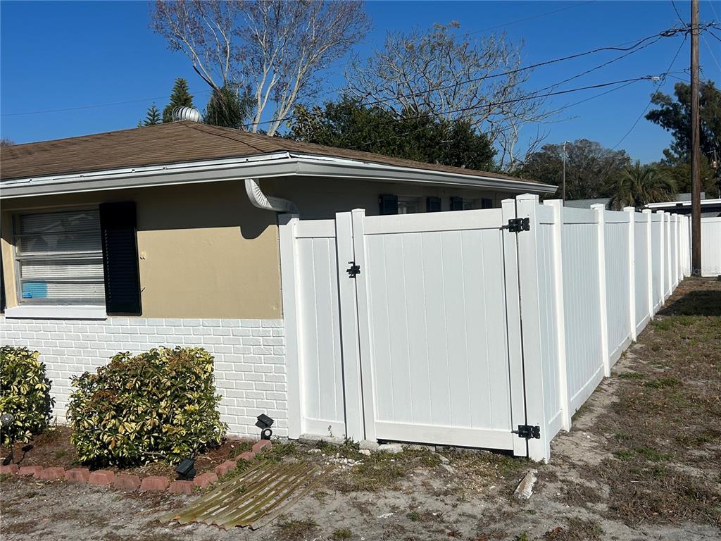 A white vinyl privacy fence runs along the side of a house with brick siding — 10824 INGLEWOOD AVENUE, PORT RICHEY, FL