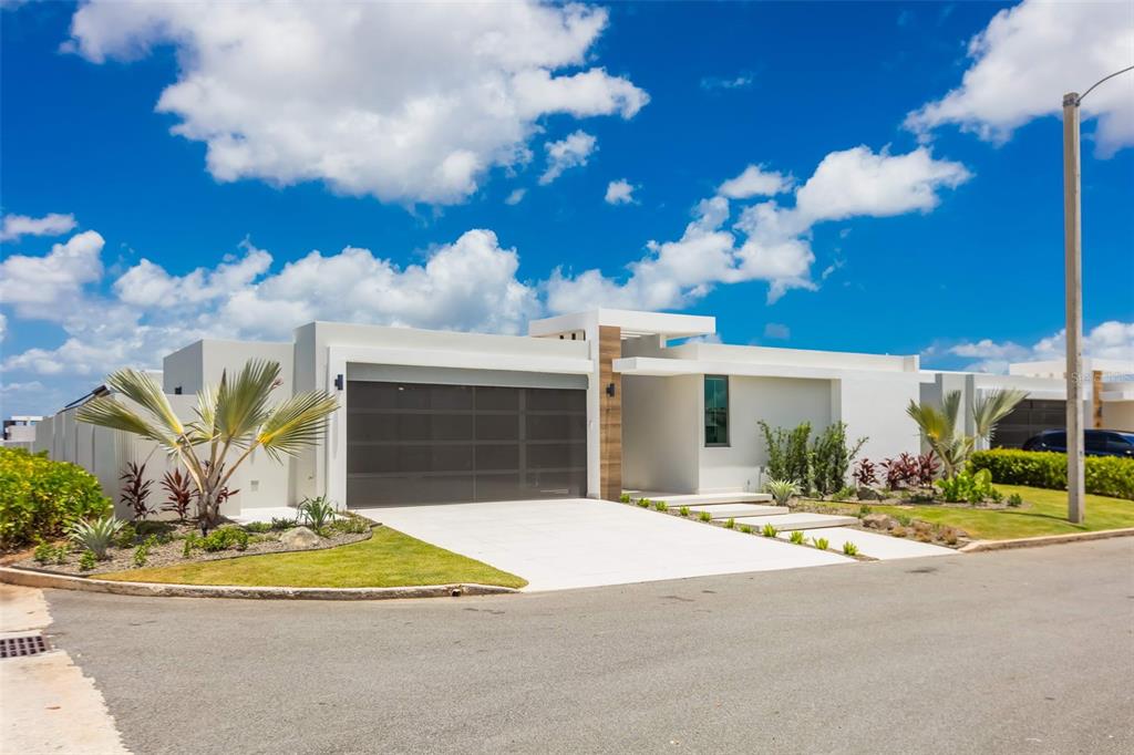 A modern, single-story white house with a flat roof and a large garage door — RESIDENCES AT RIO CALLE EBRO CORNER UNIT 69, BAYAMON, PR