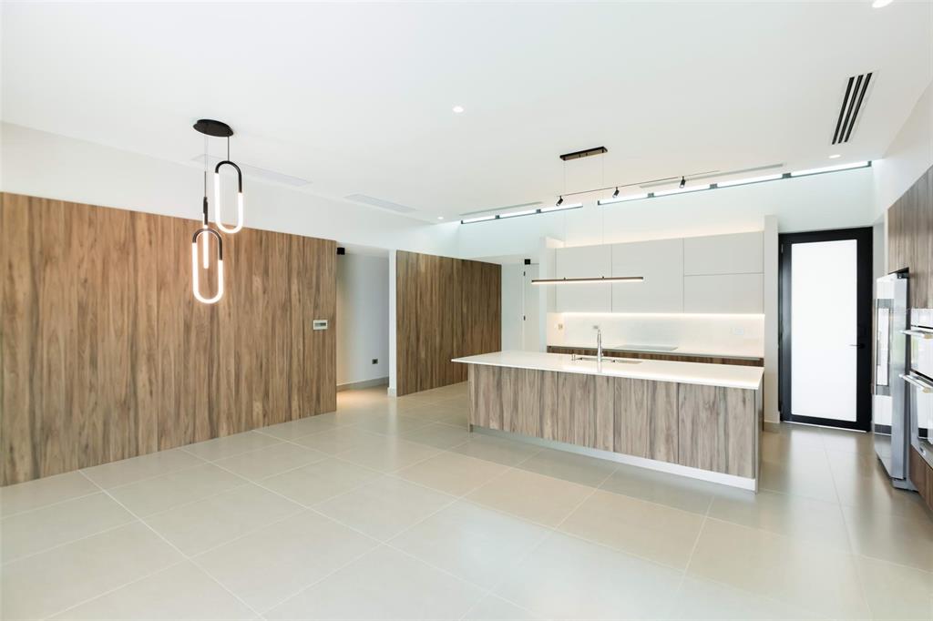 A modern kitchen features a wood-paneled island, white cabinetry, and large light-colored floor tiles — RESIDENCES AT RIO CALLE EBRO CORNER UNIT 69, BAYAMON, PR