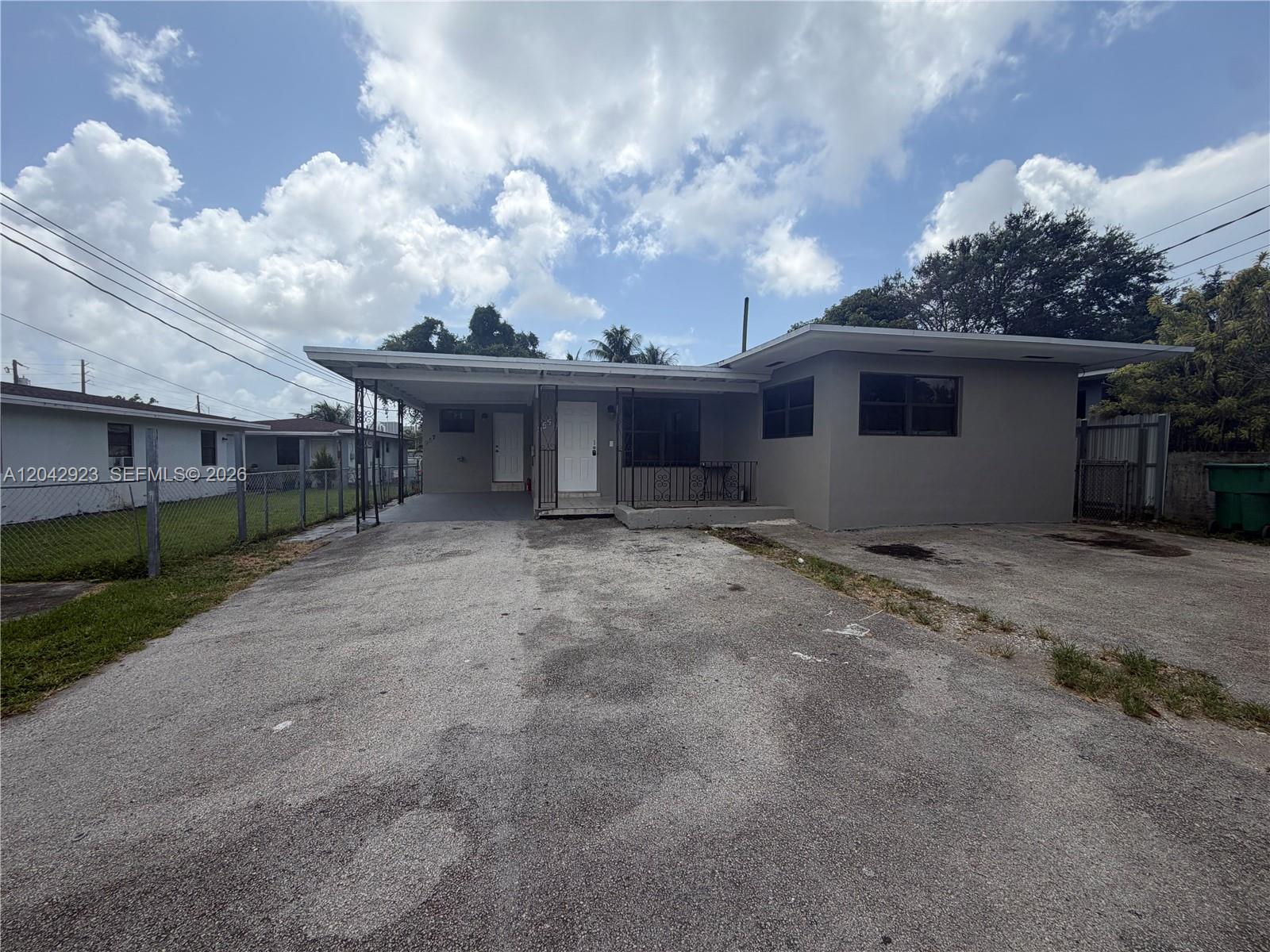 A single-story house features a gray exterior, a flat roof, and a paved driveway — MIAMI, FL