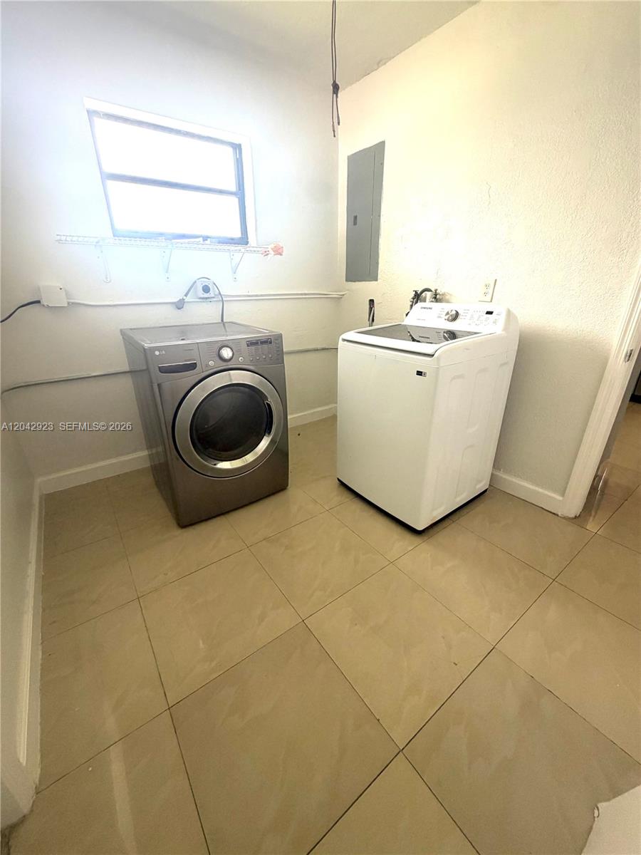 A laundry room features a stainless steel dryer, a white washing machine, and tiled floors — MIAMI, FL