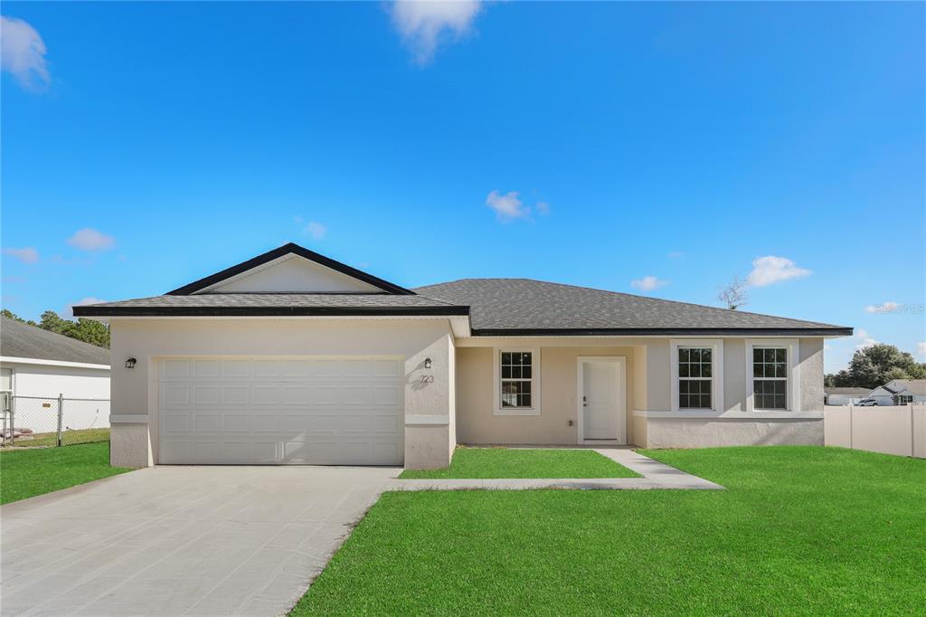 A single-story house with a white stucco exterior, a two-car garage, and a lawn — 8539 SW 129TH LANE, OCALA, FL