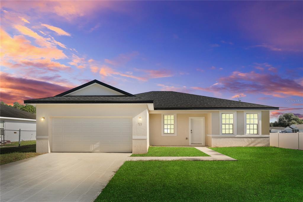 A single-story house with a two-car garage, white stucco exterior, and a green lawn — 8539 SW 129TH LANE, OCALA, FL