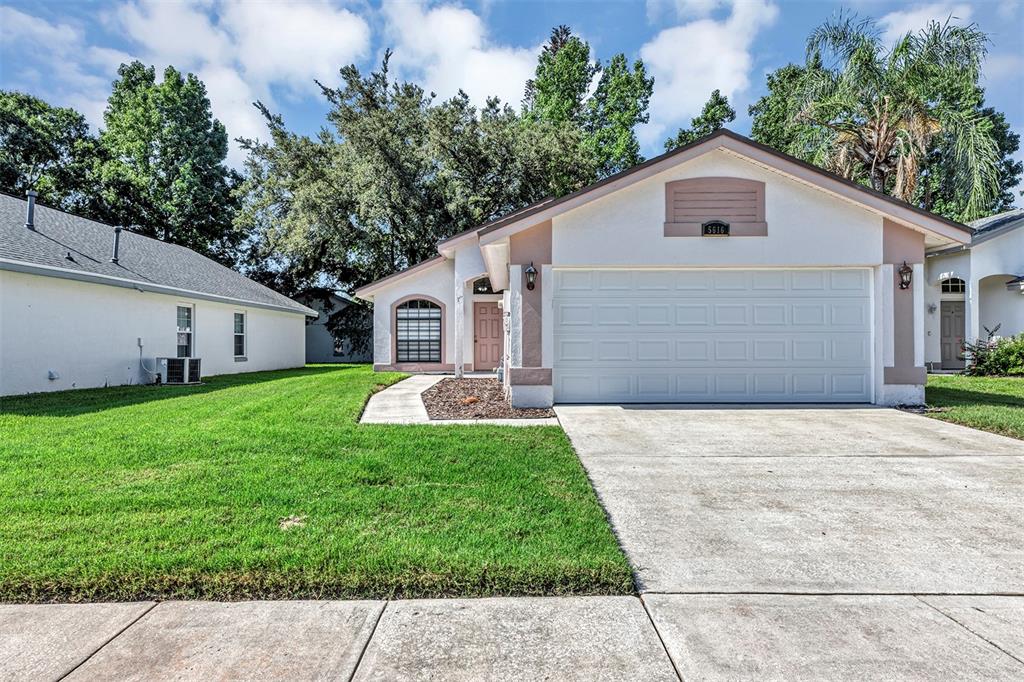 A single-story house with a white exterior, a two-car garage, and a green lawn — 5616 NORMAN H CUTSON DRIVE, ORLANDO, FL
