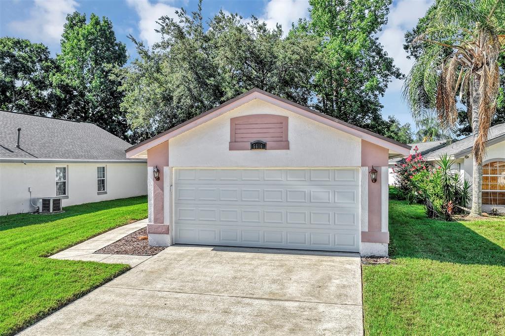 A detached, single-car garage with white stucco walls, pink trim, and a concrete driveway — 5616 NORMAN H CUTSON DRIVE, ORLANDO, FL