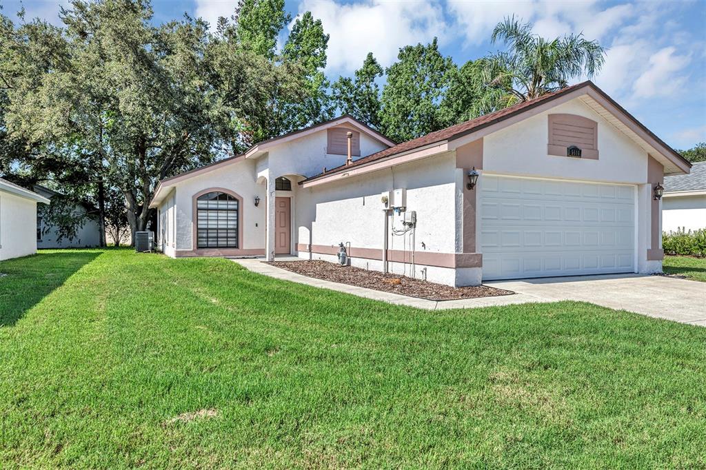 A single-story house with a white stucco exterior, a two-car garage, and a front lawn — 5616 NORMAN H CUTSON DRIVE, ORLANDO, FL