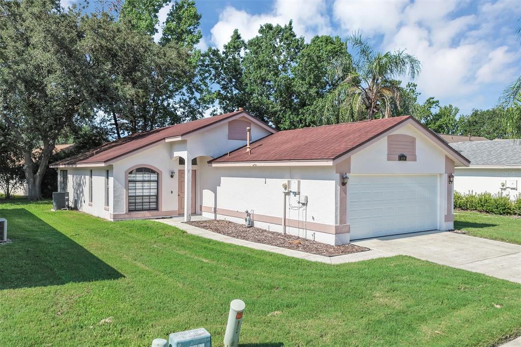 A single-story house with a white stucco exterior, a brown roof, and a two-car garage — 5616 NORMAN H CUTSON DRIVE, ORLANDO, FL