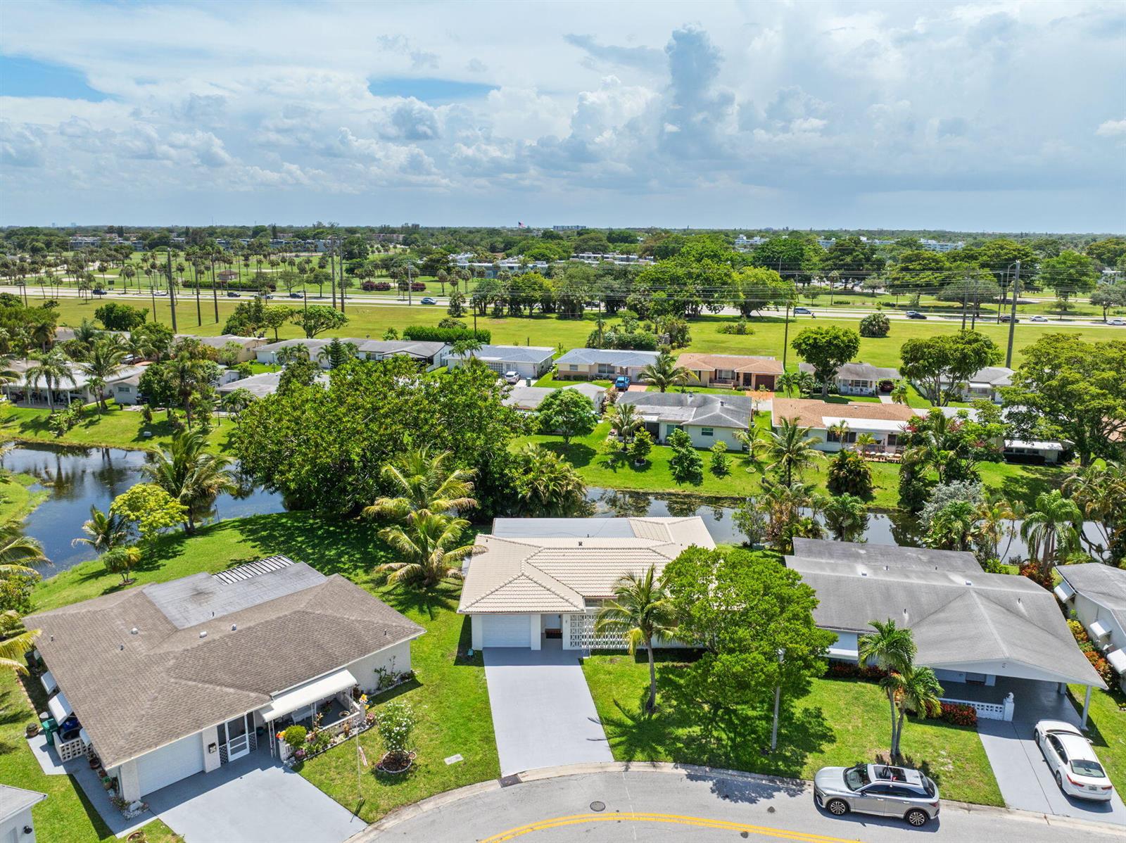 An aerial view shows three single-story houses with driveways and lawns near a small canal — 1550 NW 70th Terrace, Margate FL 33063, MARGATE, FL