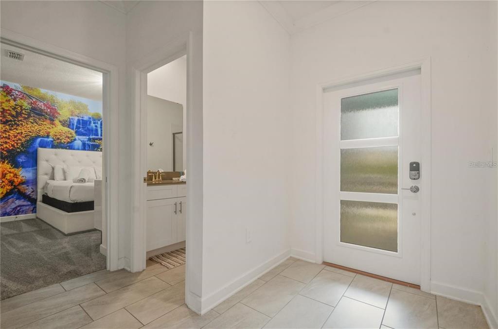 An entryway features light tile flooring, a white front door, and views into a bedroom — 4363 SCENE LN, KISSIMMEE, FL