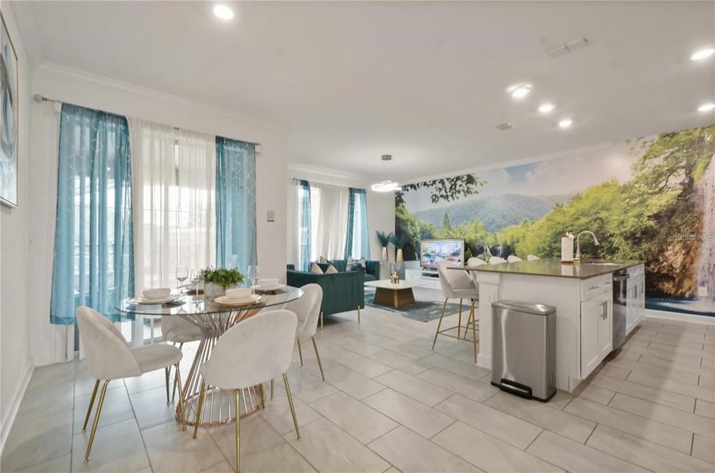 An open-concept living and dining area features a kitchen island, tile flooring, and wall mural — 4363 SCENE LN, KISSIMMEE, FL