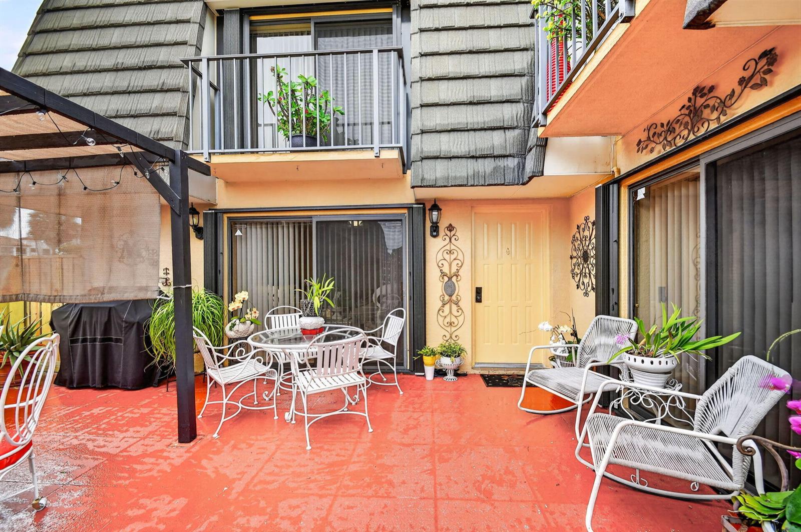 A red-tiled patio features white metal furniture, a grill, and a yellow exterior door — 315 3rd Way, West Palm Beach FL 33407, WEST PALM BEACH, FL