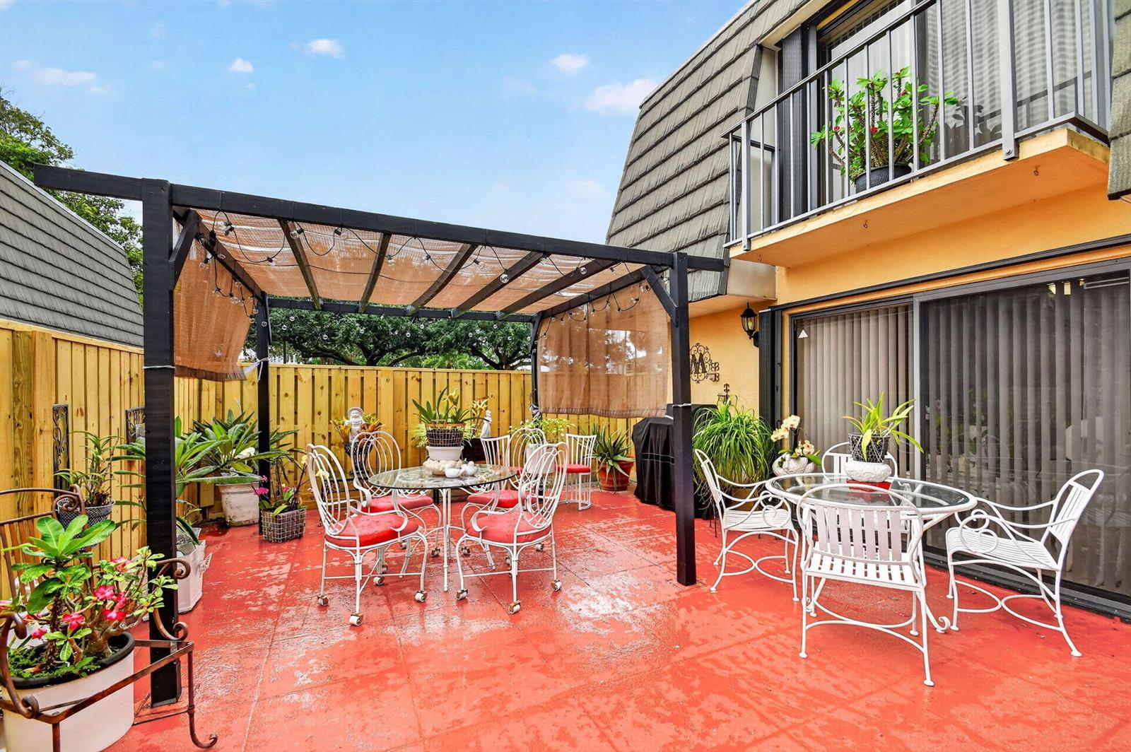 A patio with a pergola, two dining sets, and a red concrete floor — 315 3rd Way, West Palm Beach FL 33407, WEST PALM BEACH, FL
