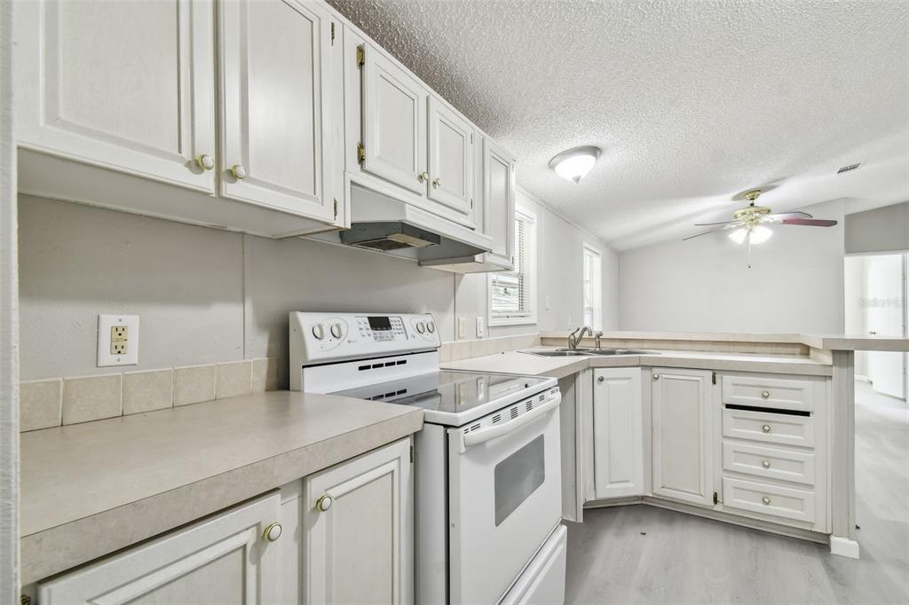 A kitchen with white cabinets, white appliances, and light-colored countertops — 10607 BAY HILLS CIRCLE, THONOTOSASSA, FL