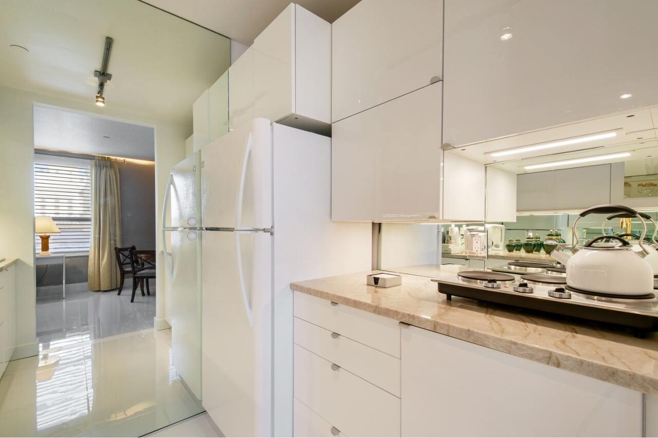 A kitchen features white glossy cabinets, a marble countertop, and a white refrigerator — 235 Sunrise Avenue # 2026, Palm Beach FL 33480, PALM BEACH, FL