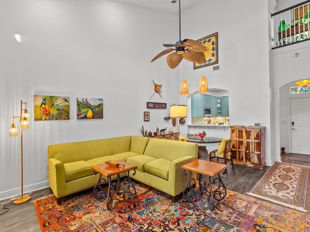 A living room features a lime green sectional sofa, a colorful area rug, and high ceilings — 1643 Baseline Lane, Vero Beach FL 32967, VERO BEACH, FL