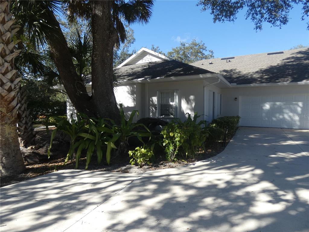 A single-story house with a white exterior, a garage, and a large tree in front — 1448 WINDING OAK DRIVE, PORT CHARLOTTE, FL