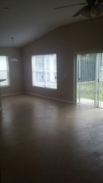 An empty living room with tile floors, a ceiling fan, and sliding glass doors — 11415 MOUNTAIN BAY DRIVE, RIVERVIEW, FL