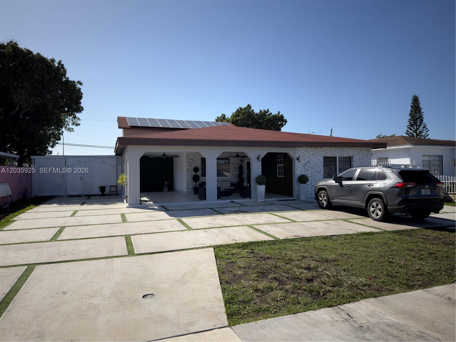 A single-story house features a covered front porch, a paved driveway, and solar panels — 224 E 42nd St, Hialeah FL 33013, HIALEAH, FL