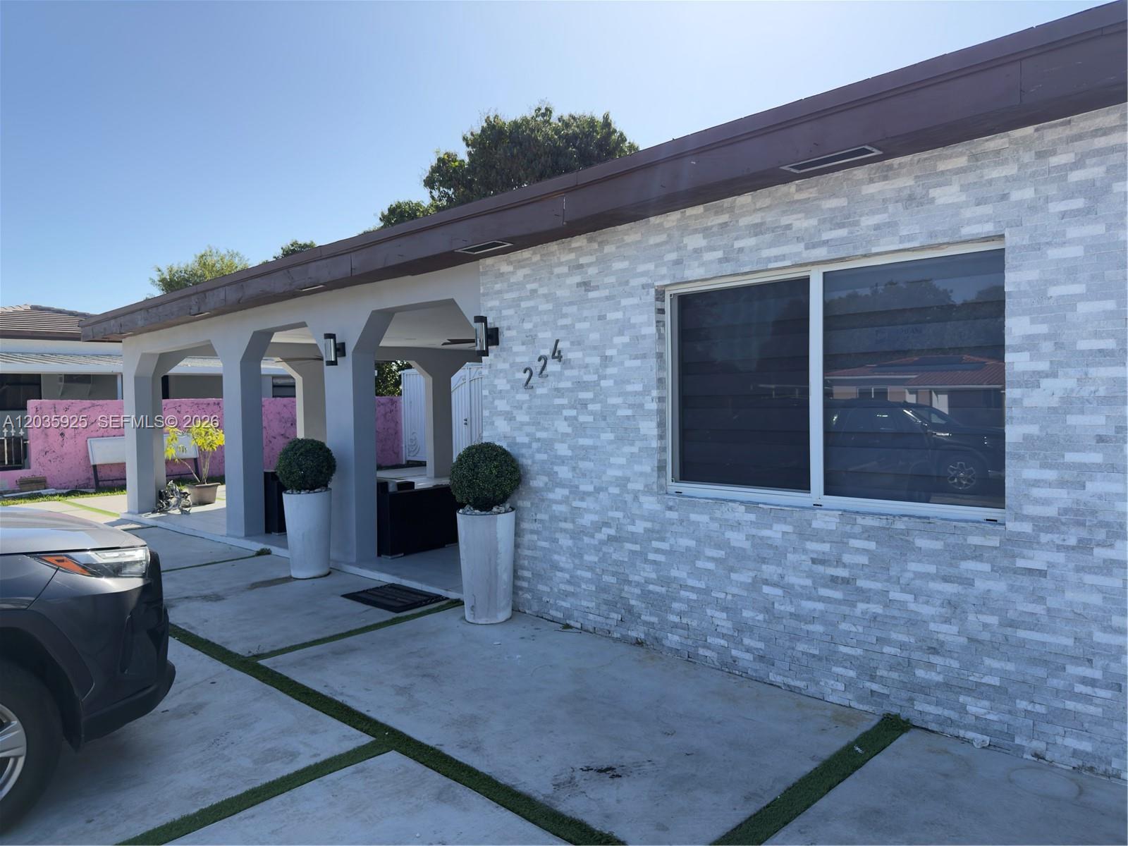 The exterior of a house features a stone-tiled facade, a covered porch, and concrete driveway — 224 E 42nd St, Hialeah FL 33013, HIALEAH, FL