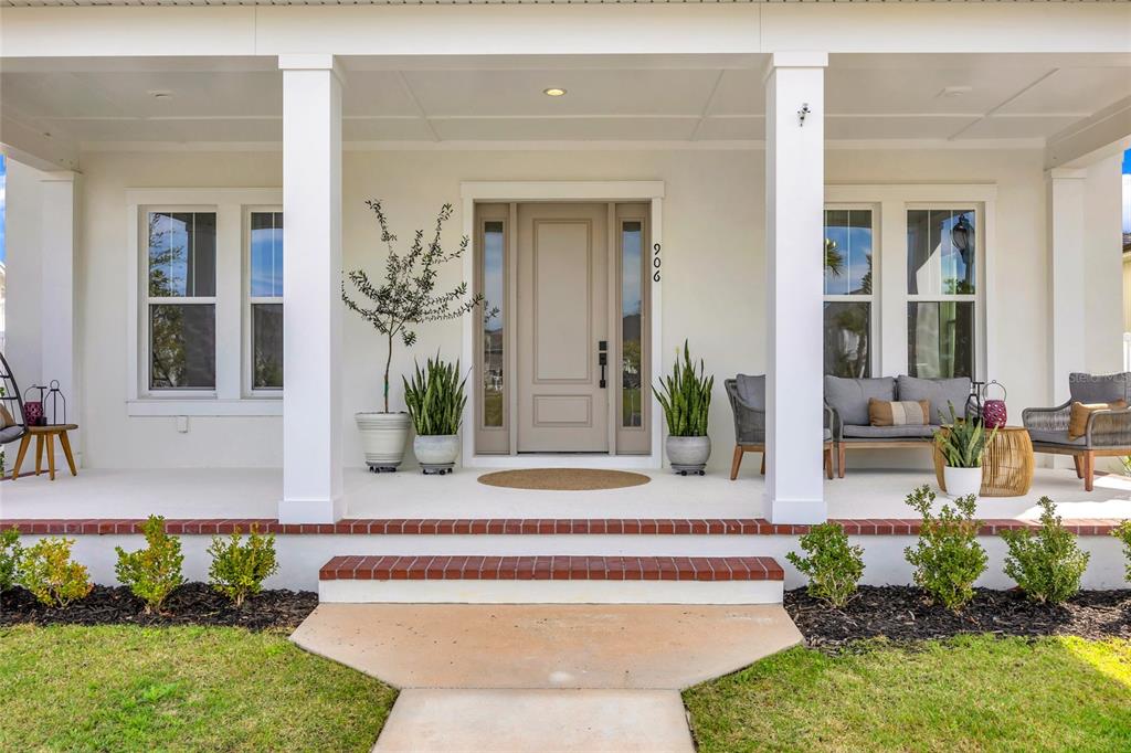 A front porch with white columns, a beige door, and patio furniture faces a lawn — 906 ALLENDALE LANE, WINTER GARDEN, FL