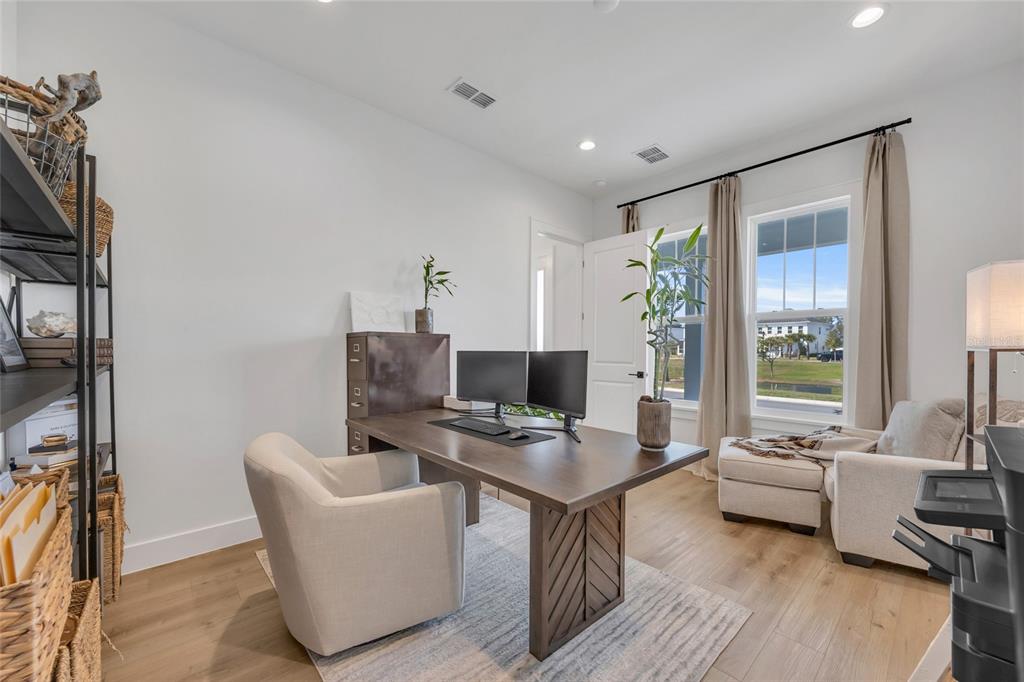 A home office features a wooden desk, dual monitors, a chair, and a window view — 906 ALLENDALE LANE, WINTER GARDEN, FL