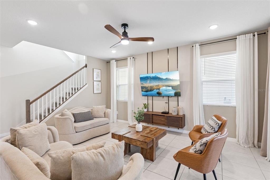 A living room features a mounted television, wooden coffee table, and a staircase — 8913 COCONUT BREEZE DRIVE, KISSIMMEE, FL