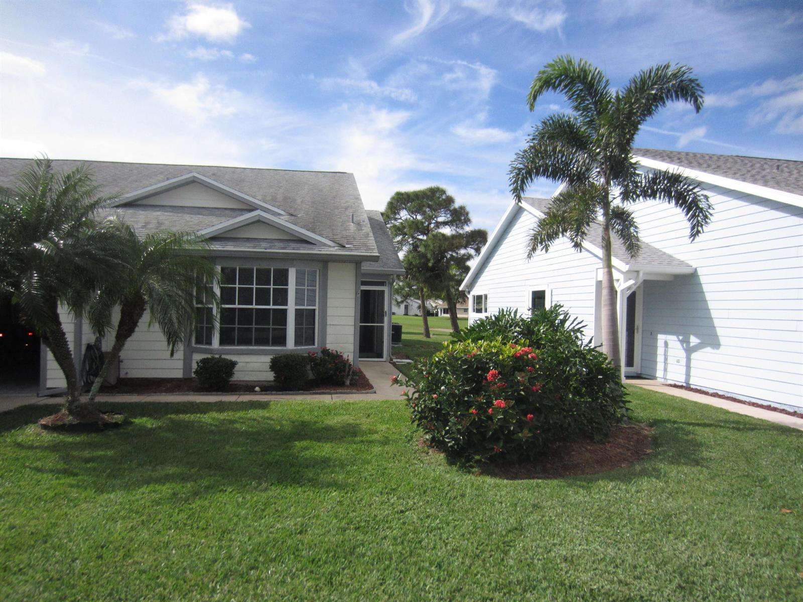 Two single-story houses with light-colored siding, palm trees, and landscaping under a blue sky — 4045 Gator Trace Road, Fort Pierce FL 34982, FORT PIERCE, FL