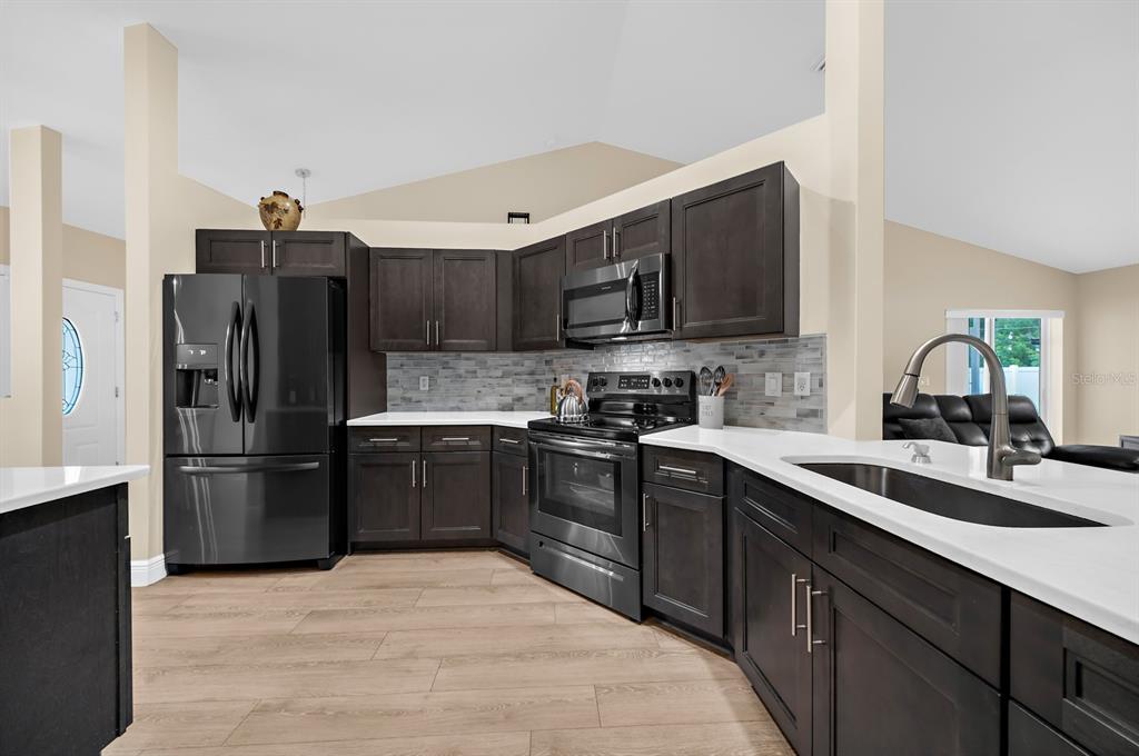 A kitchen with dark wood cabinets, stainless steel appliances, and white countertops — 5022 20TH STREET COURT E, BRADENTON, FL