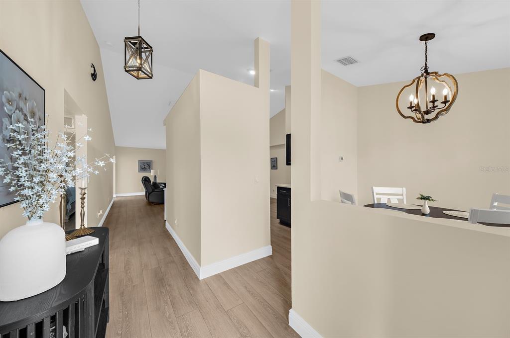 A view of a hallway and dining area with light wood flooring and pendant lighting — 5022 20TH STREET COURT E, BRADENTON, FL