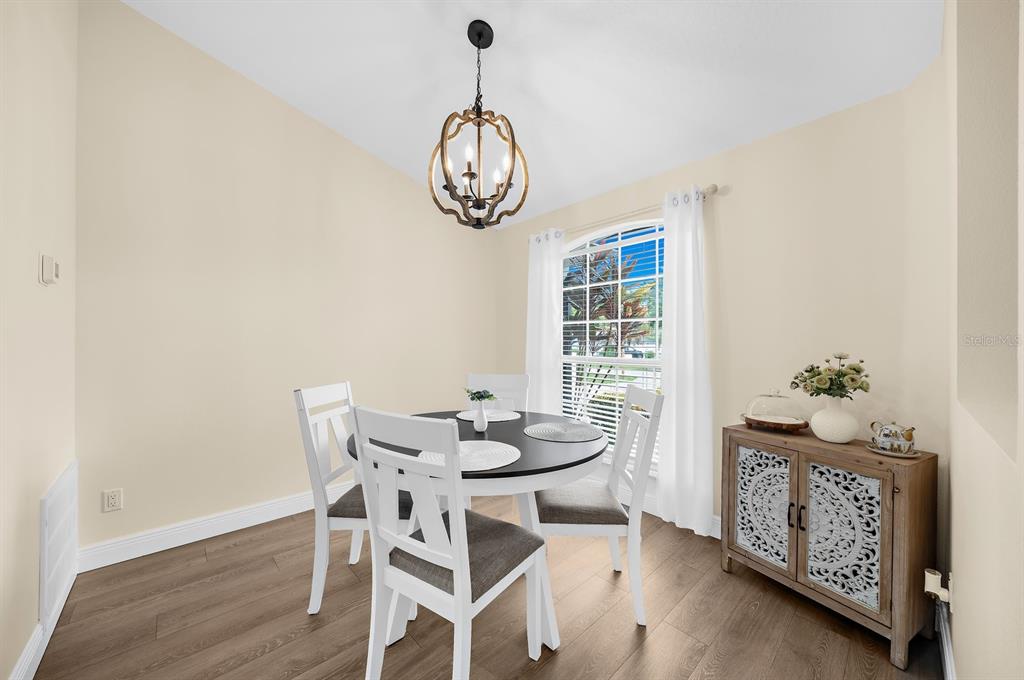 A dining area features a round table, white chairs, a chandelier, and a wooden cabinet — 5022 20TH STREET COURT E, BRADENTON, FL