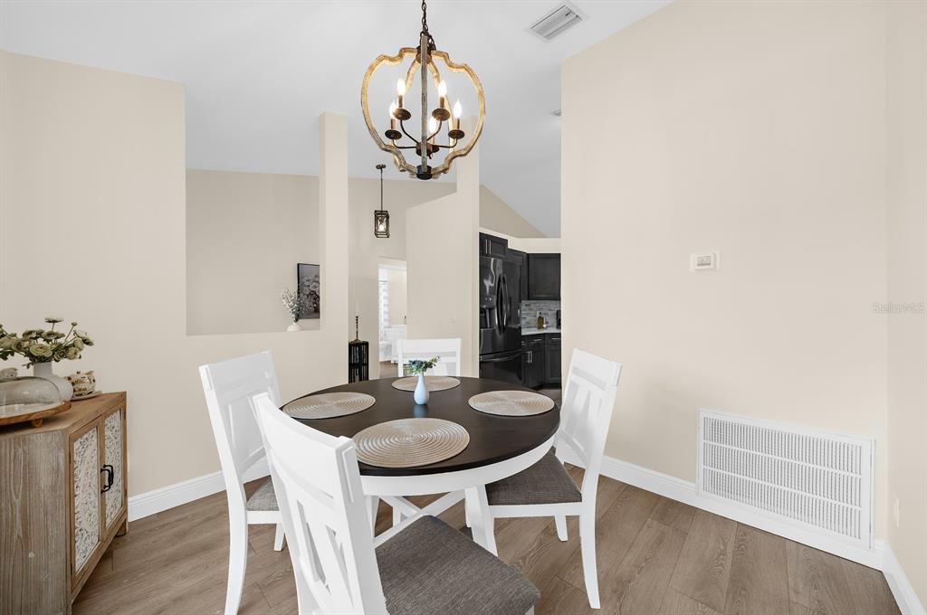 A dining area features a round table, white chairs, and a rustic chandelier — 5022 20TH STREET COURT E, BRADENTON, FL
