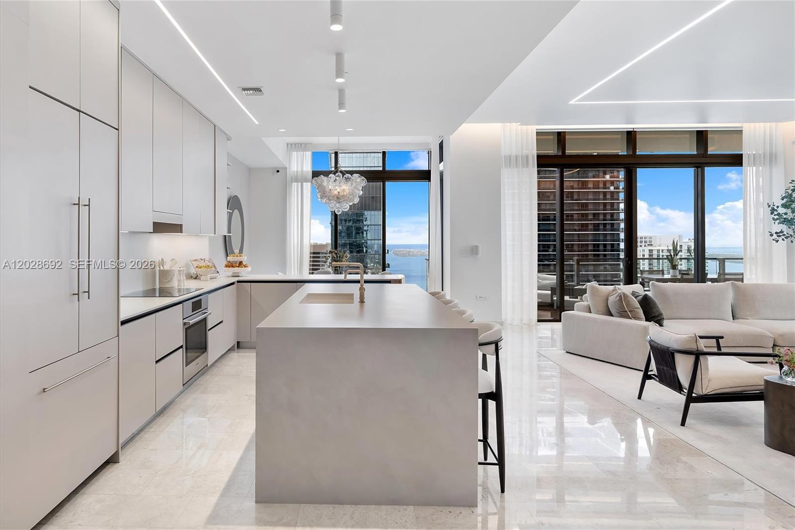 A modern kitchen with a large island and light cabinetry opens to a living area — 88 SW 7th St # 4001, Miami FL 33130, MIAMI, FL