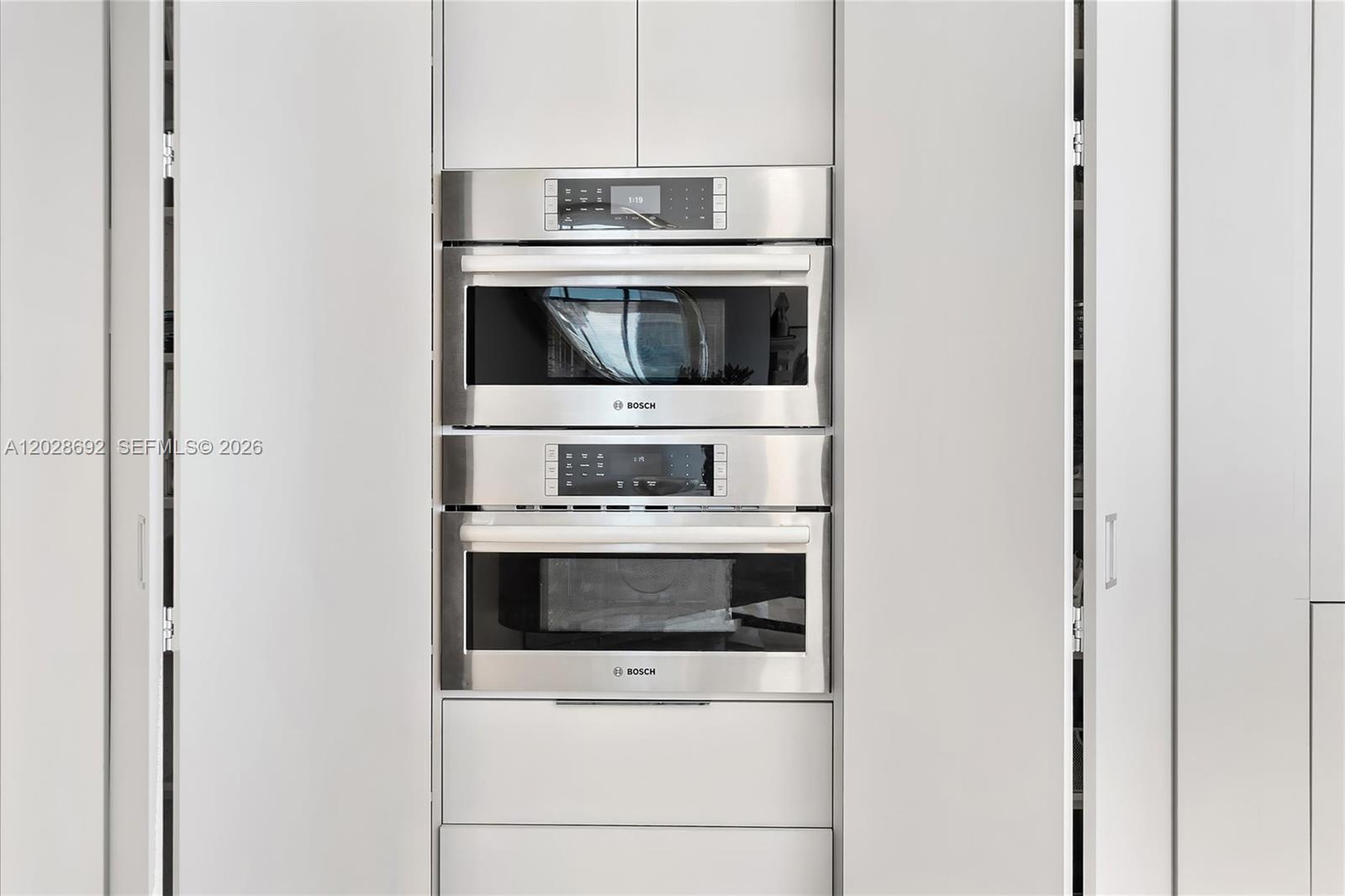A kitchen wall features two stacked stainless steel Bosch ovens set within light-colored cabinetry — 88 SW 7th St # 4001, Miami FL 33130, MIAMI, FL