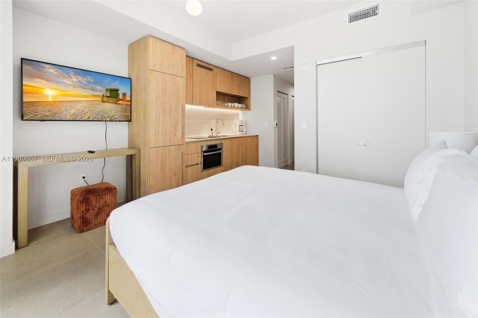 A bedroom features a bed, a small kitchenette with light wood cabinets, and a television — 11 NE 6th St # 1802, Miami FL 33132, MIAMI, FL