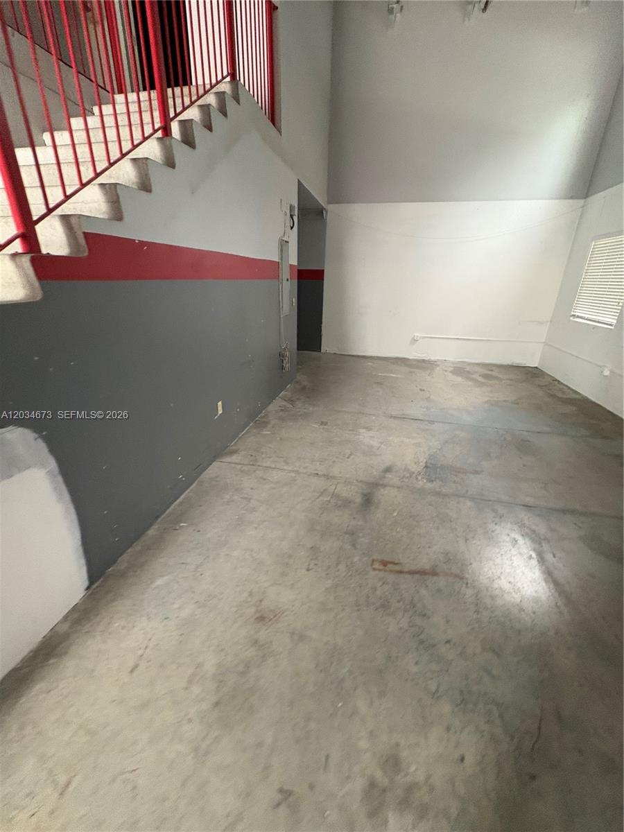 An interior view shows a concrete floor, a red-railed staircase, and gray walls — 12491 SW 134th Ct # 17, Miami FL 33186, MIAMI, FL