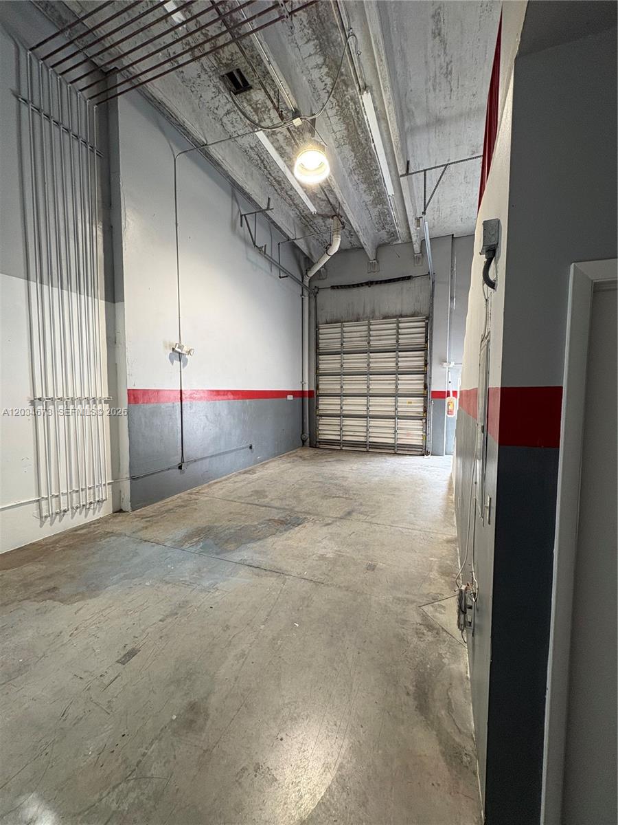 An industrial warehouse space features high ceilings, a roll-up door, and concrete flooring — 12491 SW 134th Ct # 17, Miami FL 33186, MIAMI, FL