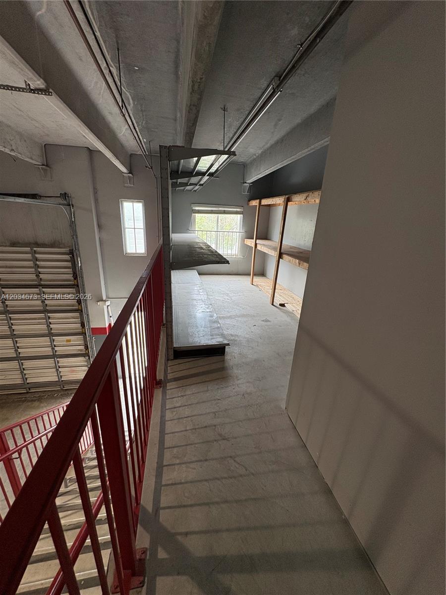 This industrial-style mezzanine features a red metal railing, concrete flooring, and wooden storage shelving — 12491 SW 134th Ct # 17, Miami FL 33186, MIAMI, FL