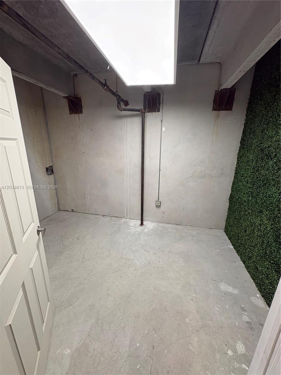 An unfinished utility room features exposed concrete walls, a vertical pipe, and a green wall — 12491 SW 134th Ct # 17, Miami FL 33186, MIAMI, FL