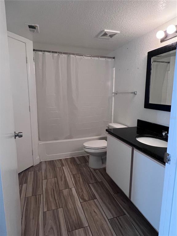 A bathroom features a shower-tub combination, a white toilet, and a vanity with black countertops — 2208 ANTIGUA PLACE UNIT 938, KISSIMMEE, FL