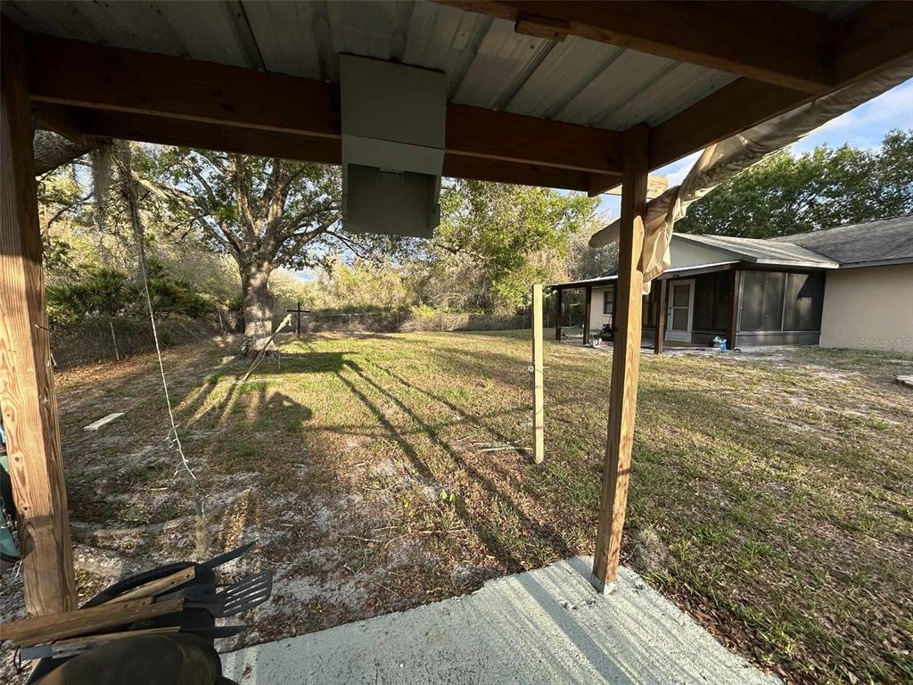 A view from a covered patio looking out toward a grassy backyard and house — 3137 CARLTON AVENUE, LAKE PLACID, FL