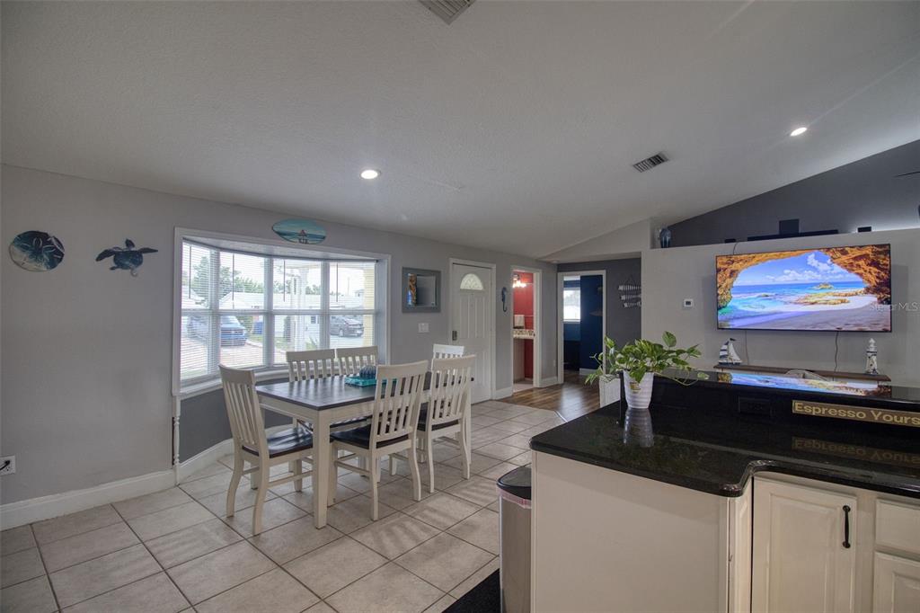 A dining area with a bay window and a kitchen counter with a television mounted above — 3652 WESTCHESTER DRIVE, HOLIDAY, FL