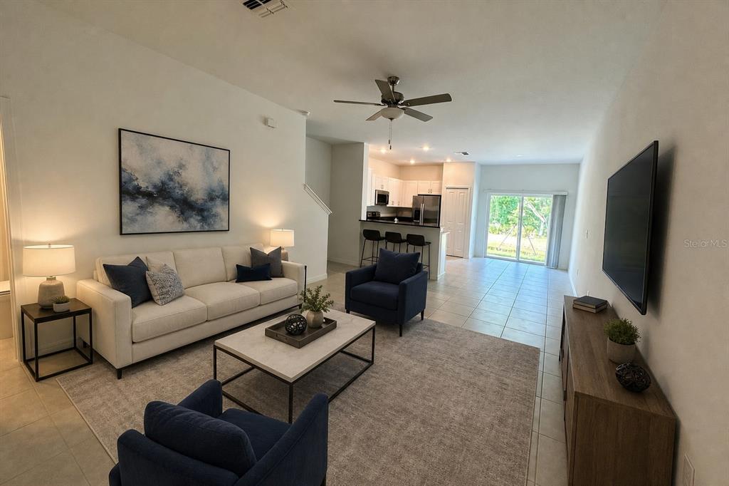 A living room with a white sofa, two blue armchairs, and an open kitchen — 17649 NECTAR FLUME DRIVE, LAND O LAKES, FL