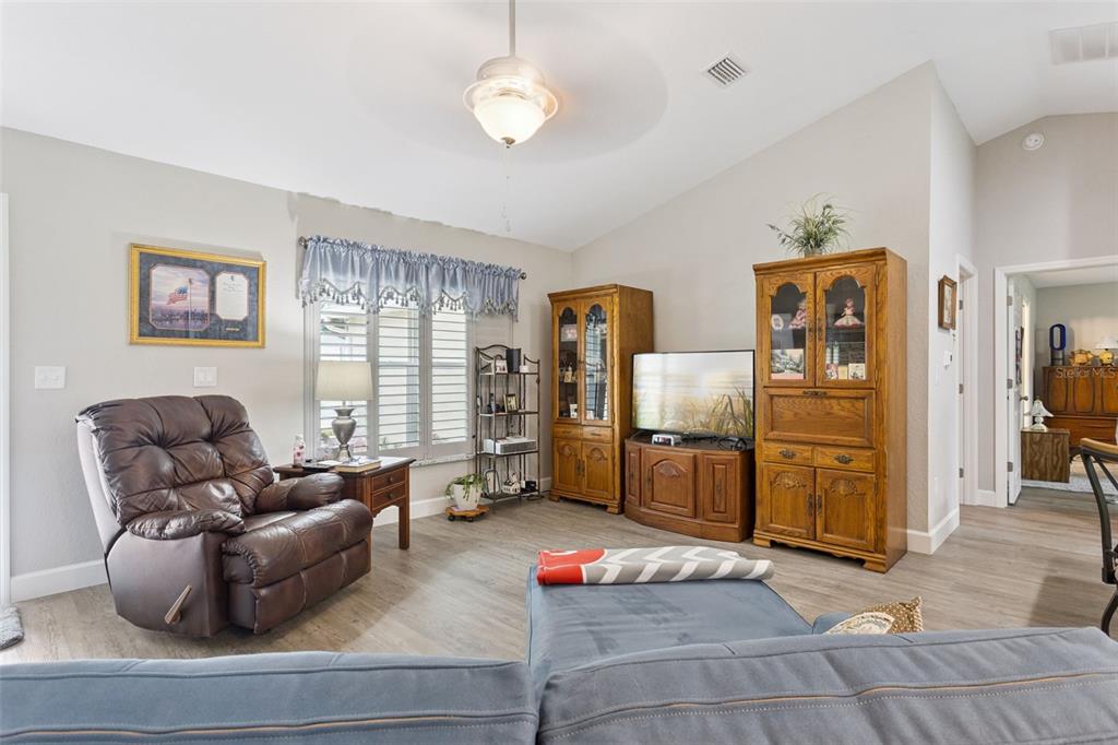 A living room features a brown leather recliner, wooden cabinets, a television, and light flooring — 13662 SE 55TH AVENUE, SUMMERFIELD, FL