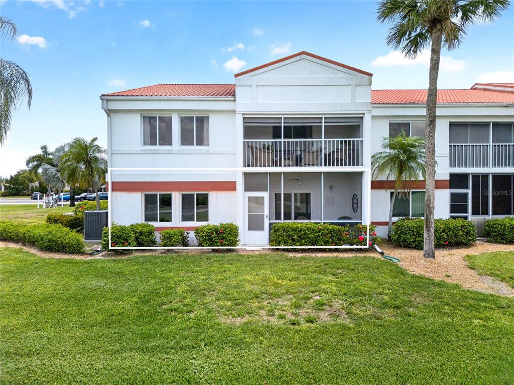 The exterior of a two-story residential building features a ground-floor screened patio and landscaping — 1990 LEISURE DRIVE UNIT 3, FORT MYERS, FL