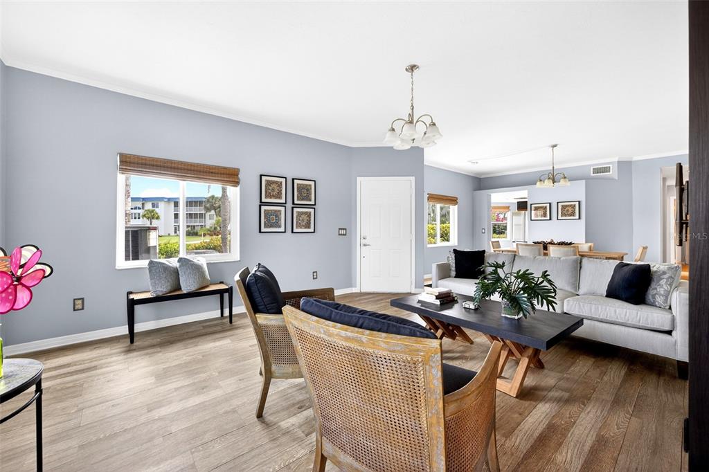 A living room with light blue walls, wood-look flooring, a sofa, and two rattan chairs — 1990 LEISURE DRIVE UNIT 3, FORT MYERS, FL