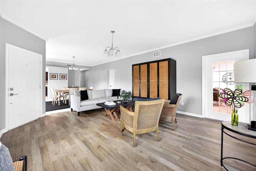 A living room with gray walls, wood-look flooring, a white sofa, and a dining area — 1990 LEISURE DRIVE UNIT 3, FORT MYERS, FL