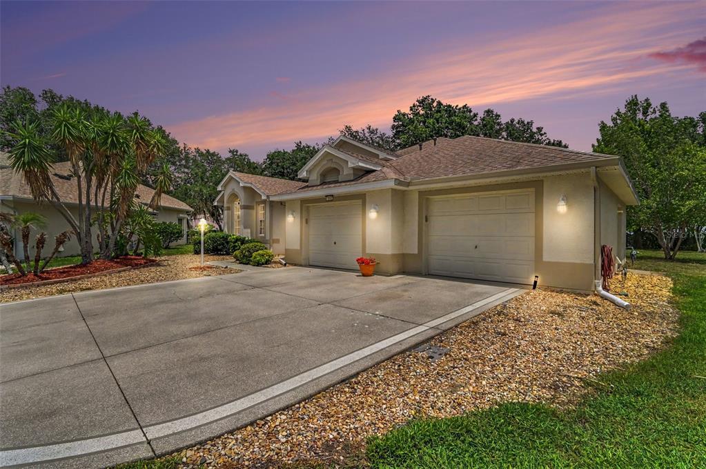 A single-story house with a two-car garage, beige stucco exterior, and a gravel front yard — 2852 CAPE HORN COURT, TAVARES, FL